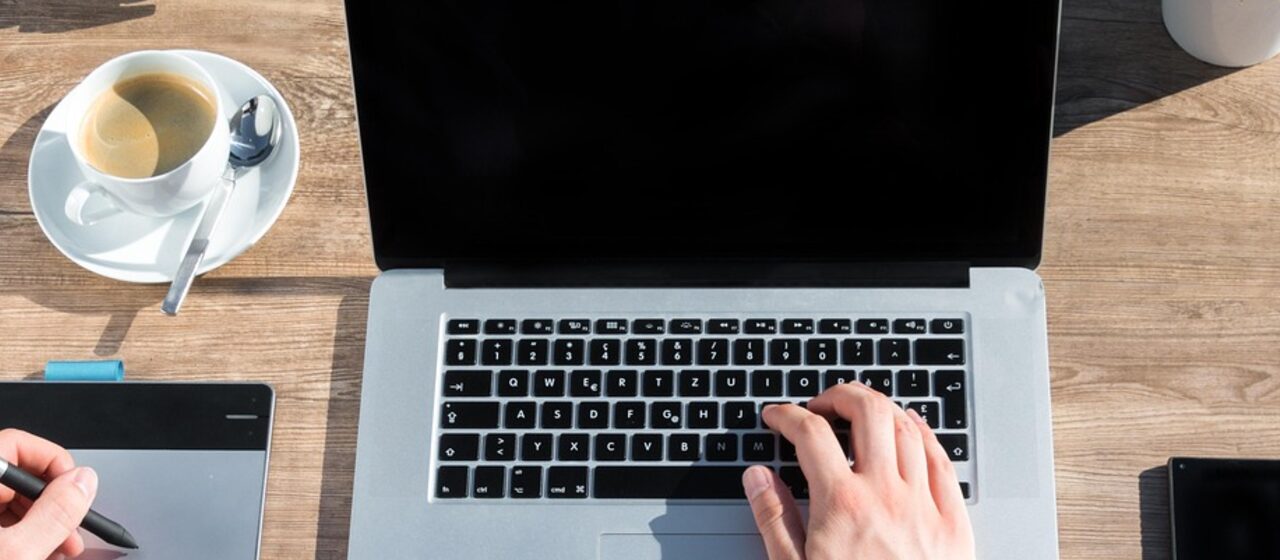 A web designer's desk with a drawing tablet, laptop and coffee