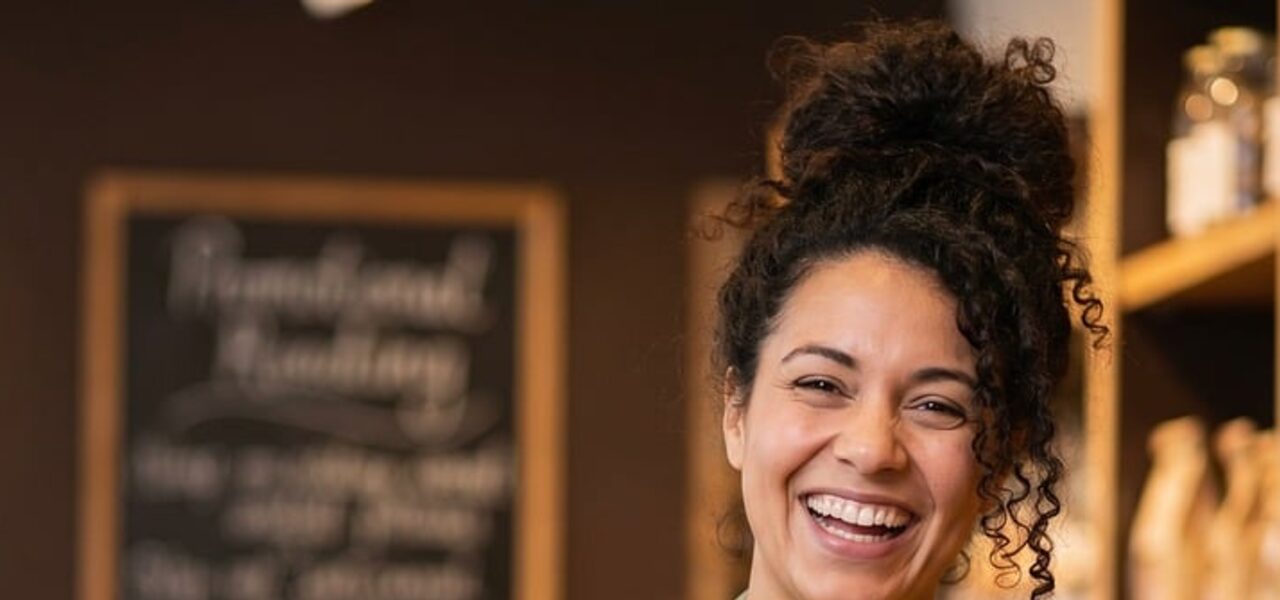 A smiling bakery owner holding a fresh loaf in her shop